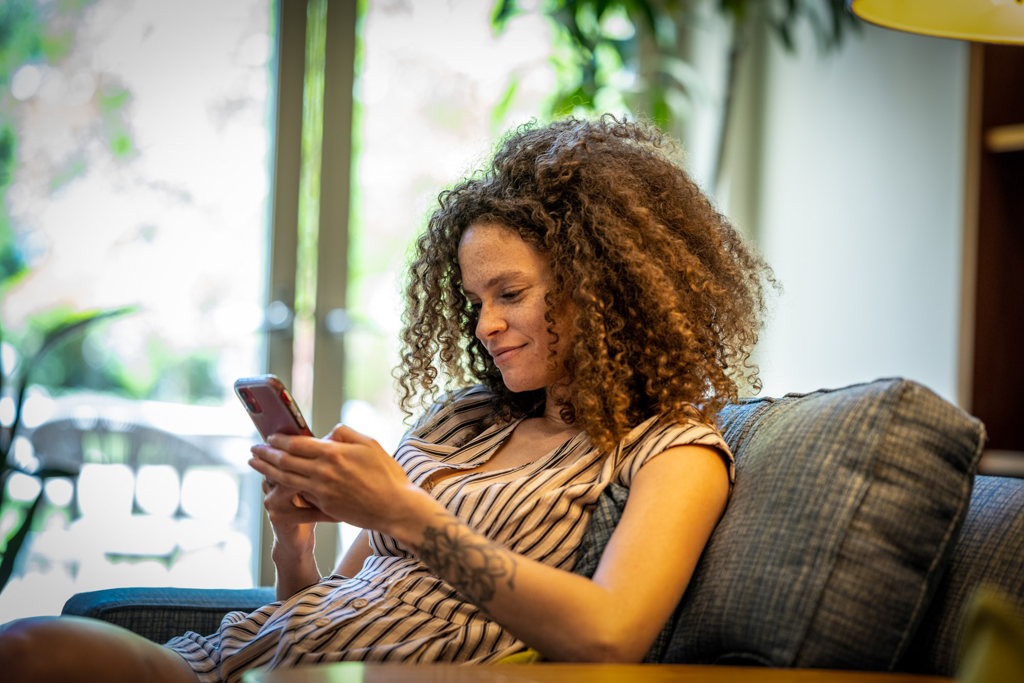 A woman focuses on her cell phone in a common area.